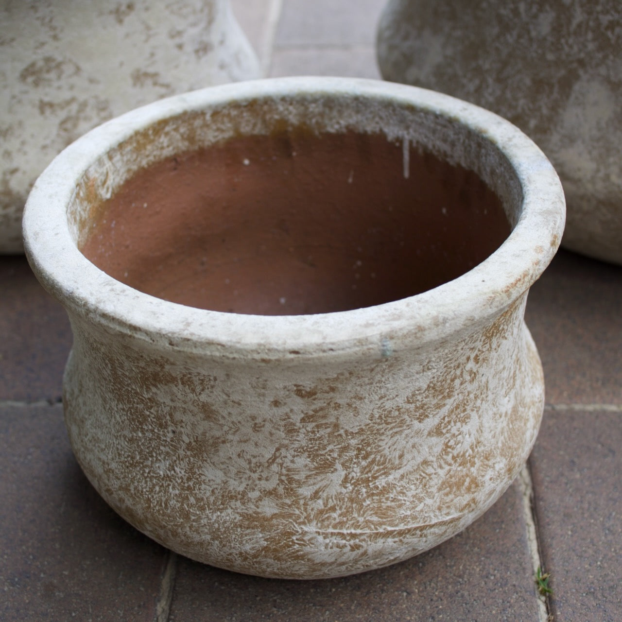 Rustica Low Lotus Pots in multiple sizes with a weathered antique finish, displayed as elegant feature pots at Brookfield Gardens, Brisbane.