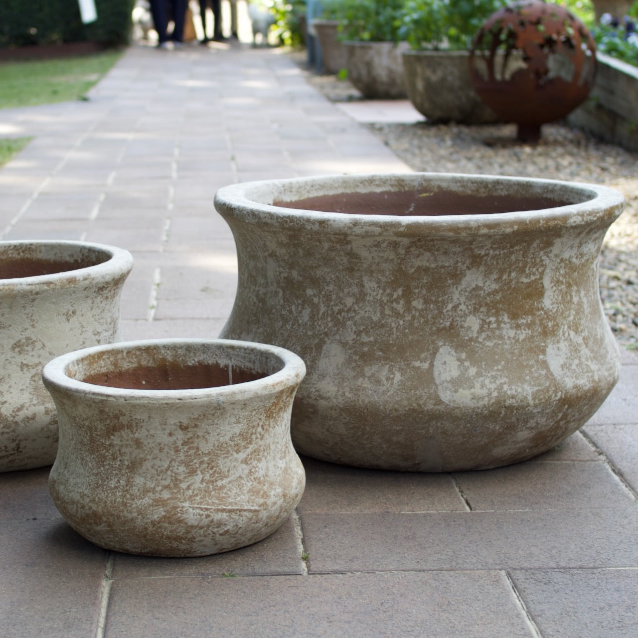 Rustica Low Lotus Pots in multiple sizes with a weathered antique finish, displayed as elegant feature pots at Brookfield Gardens, Brisbane.