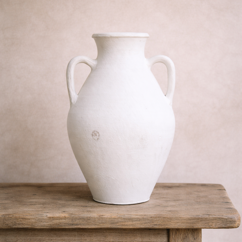 Antique Turkish double handled white terracotta urn with aged patina styled on a timber table.