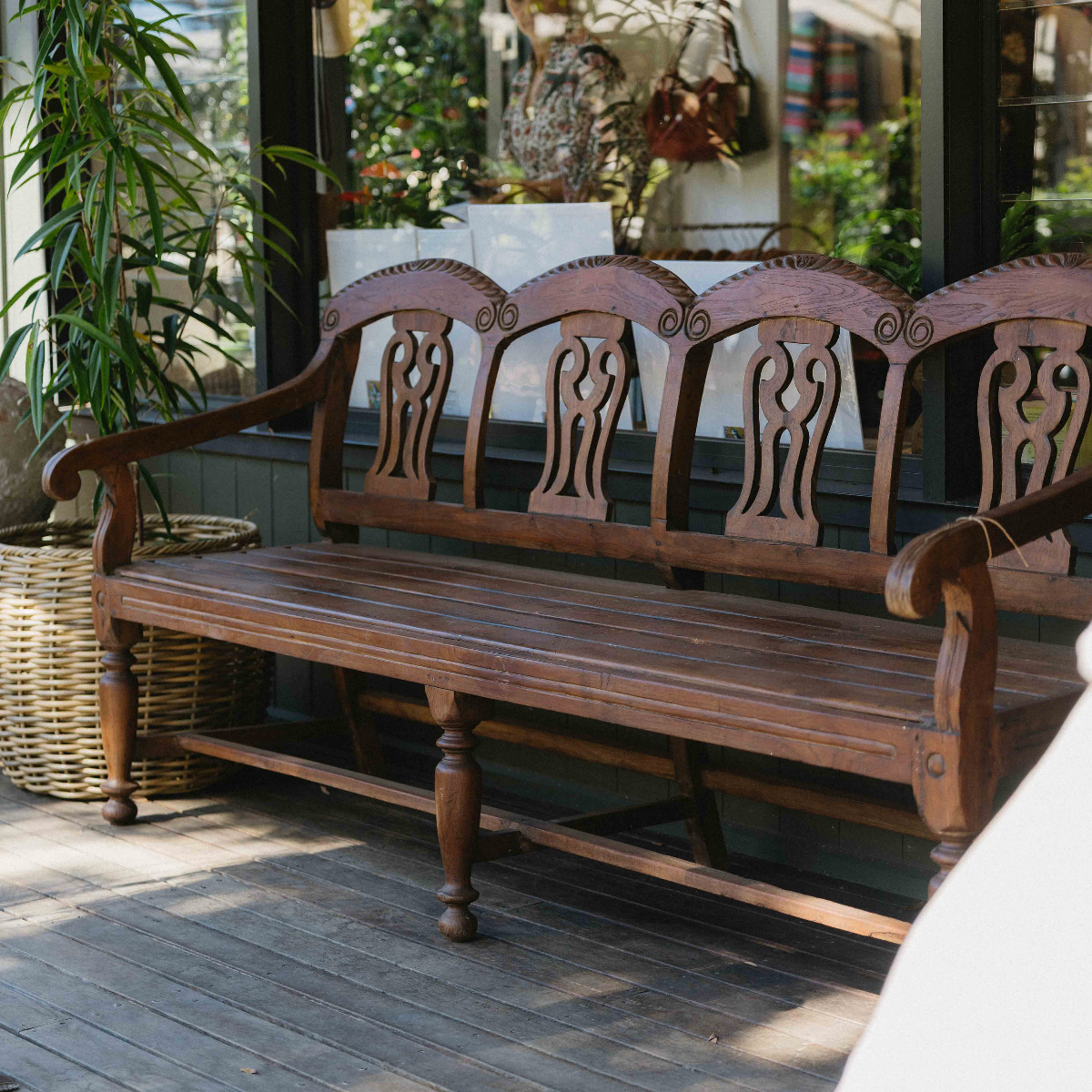 One-of-a-kind vintage Indian carved timber bench with decorative carved back, curved arms and aged timber patina at Brookfield Gardens Brisbane.